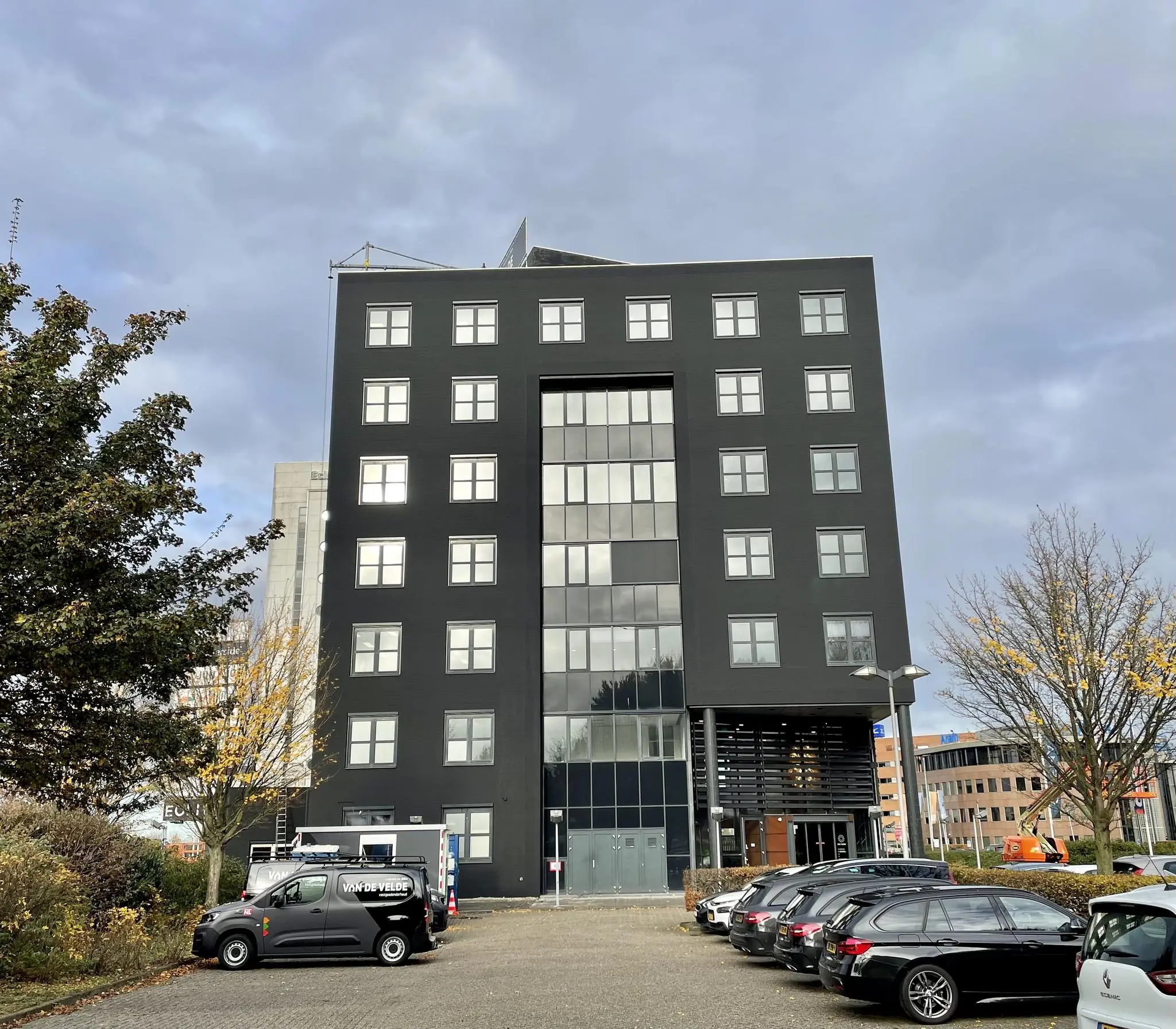 Zwart kantoorgebouw aan het Rivium Quadrant met geparkeerde auto's op de voorgrond.